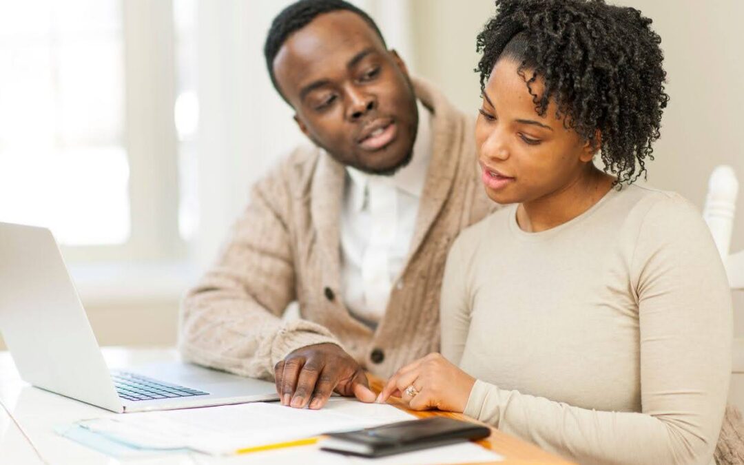 Young adults sitting at a table with financial documents and a laptop while planning for future long-term care and financial security.